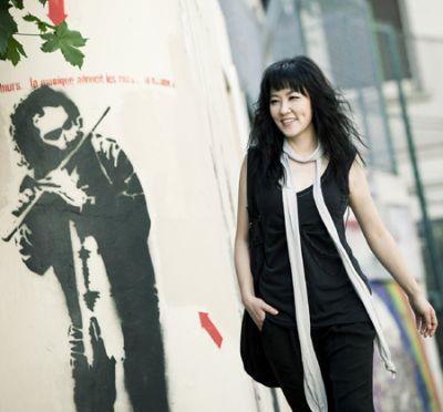 Youn Sun Nah marche deavnat un affiche qui représente un flutiste