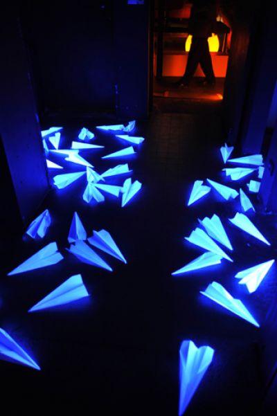 des avions en papier jonchent le sol dans une lumière bleutée saturée